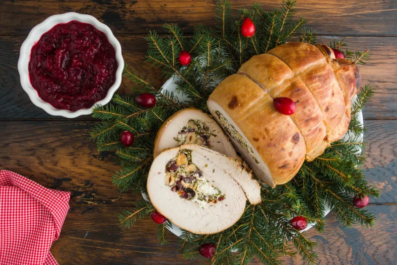 baked turkey breast roll stuffed with feta cheese, hazelnuts, cranberries and parsley, christmas decoration, top view
