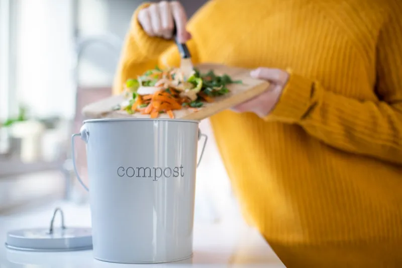 close up of woman making compost from vegetable leftovers in kitchen