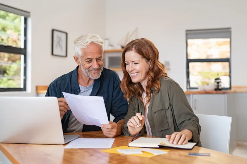 mature smiling couple sitting and managing expenses at home happy senior man and mid woman paying bills and managing budget middle aged couple checking accountancy and bills while looking at receipt