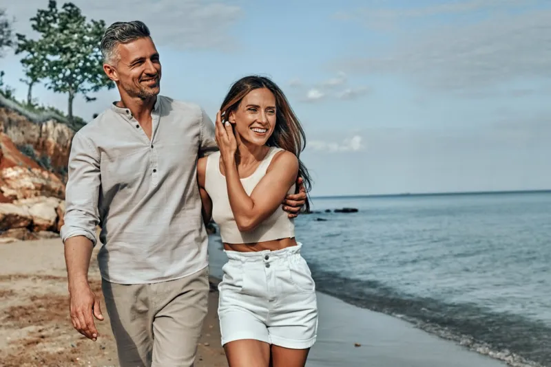 happy attractive couple walking on beautiful sunny beach copy space