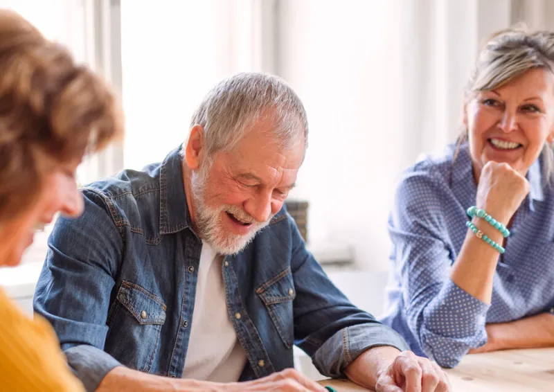 group of senior people sitting at the table in community center club, playing board games