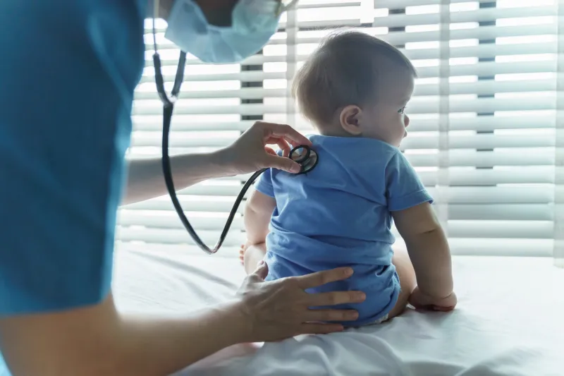 asian female pediatrician doctor examining her little baby patient with stethoscope in medical room at hospital