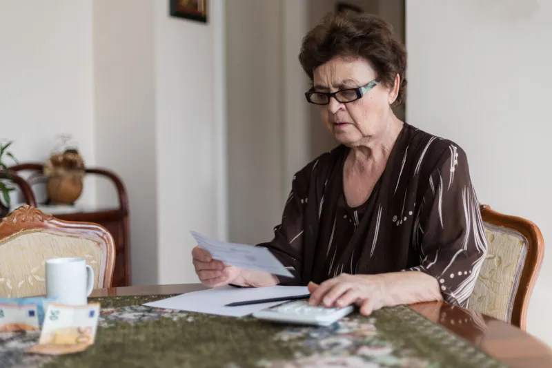 worried old woman is checking all bills for the last month while trying to calculate expenses senior woman is calculating bills at home