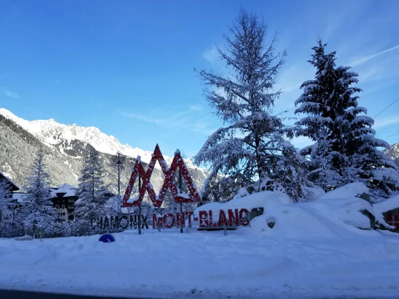 a snowy landscape surrounds the iconic chamonix mont-blanc sign, showcasing the beauty of winter in the french alps on a clear december day