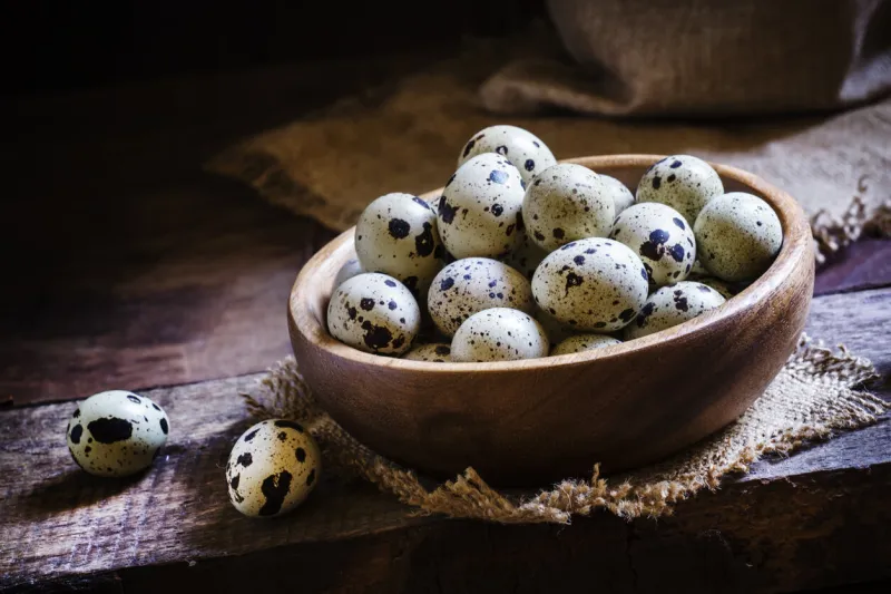 quail eggs in a bowl, vintage wooden background, rustic style low key, selective focus