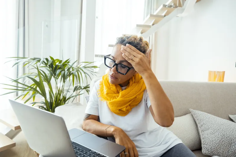 frustrated sad woman feeling tired worried about problem sitting on sofa with laptop, stressed depressed girl troubled with reading bad news online, email notification about debt or negative message