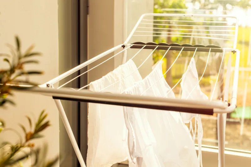 hanging laundry on balcony on the drying rack opposite sea and palm trees view at sunset sunshine