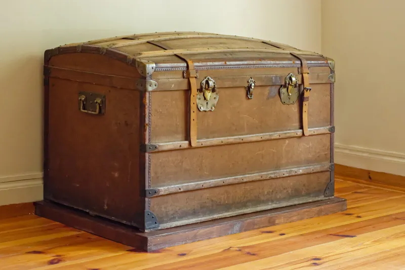 old leather chest with iron brackets in the corner of the room