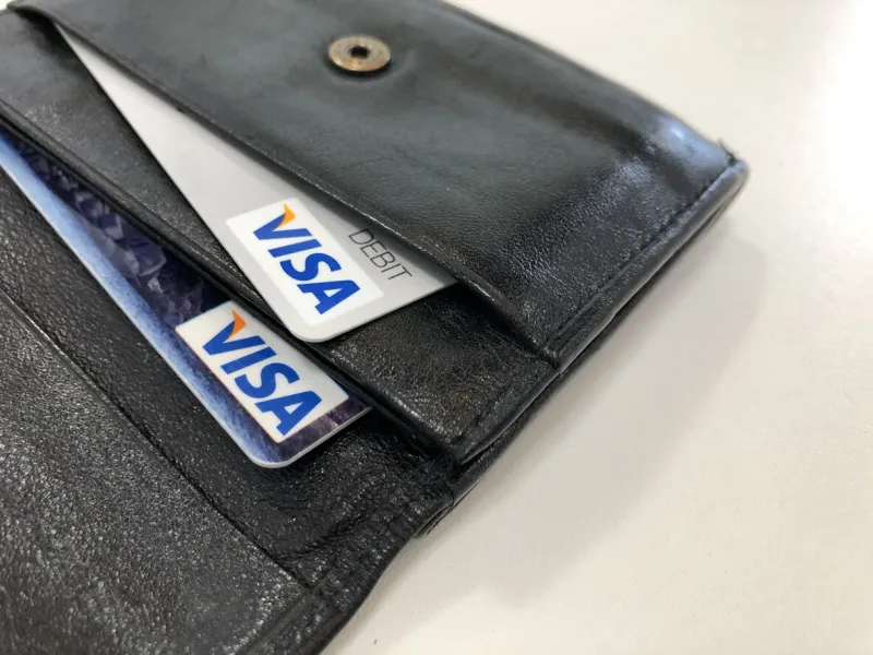 munich, germany bavaria - may 22, 2021  visa credit and debit cards in a black leather wallet with a white table surface background