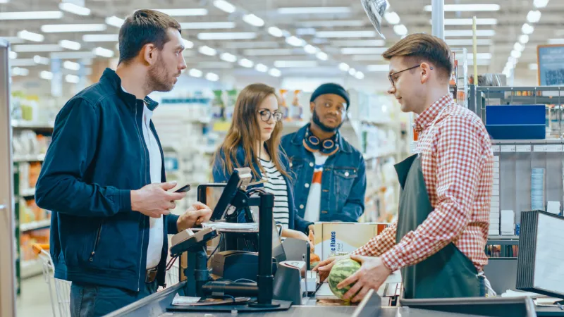 at the supermarket  checkout counter customer pays with smartphone for his items big shopping mall with friendly cashier, small lines and modern wireless paying terminal system