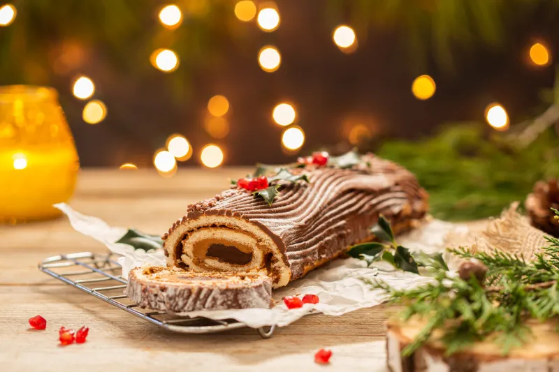 traditional christmas cake, chocolate yule log on a rustic table with festive holiday decorations and lights