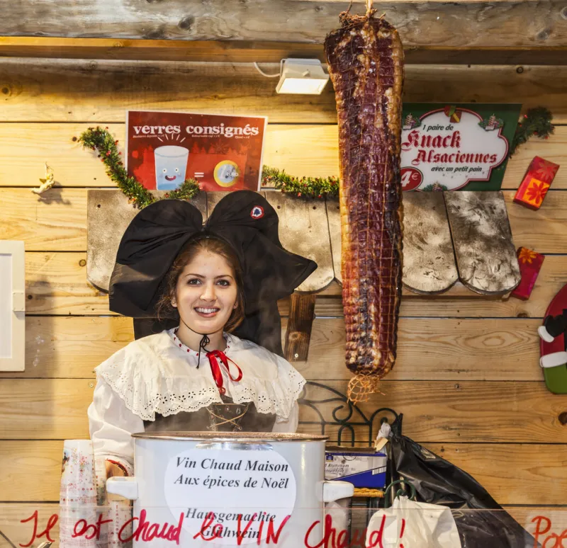 colmar, france - december 06, 2012  environmental portrait of a young woman selling hot wine in a kiosk during the christmas market in colmar, alsace,france
