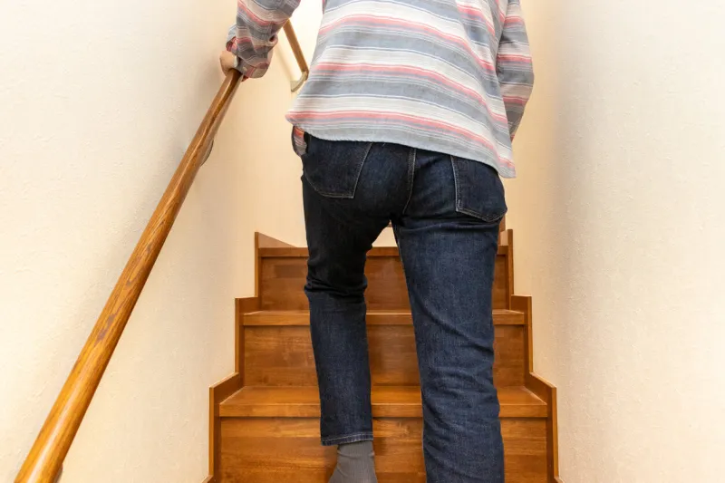 rear view of a man holding the handrail and climbing the stairs