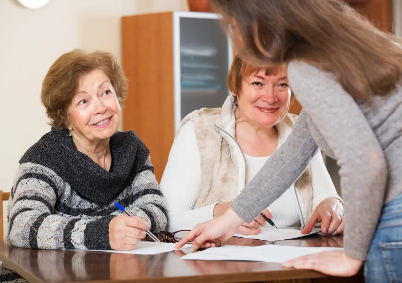 young woman agent consulting cheerful elderly women in office