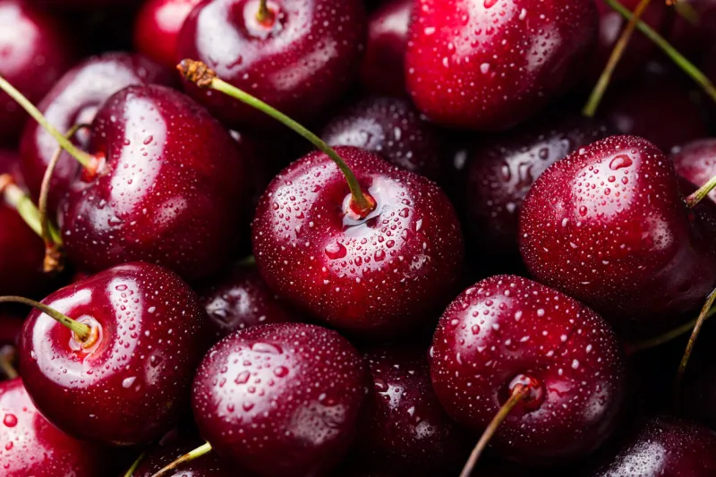 fresh ripe black cherries on a blue stone background top view close up