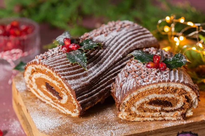 traditional christmas cake, chocolate yule log on a rustic table with festive holiday decorations and lights