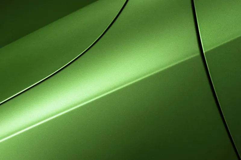 surface of green sport sedan car, detail of metal hood, fender and door of vehicle bodywork