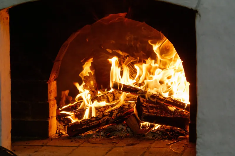 a fire is burning in a brick oven the fire is very hot and the logs are burning brightly