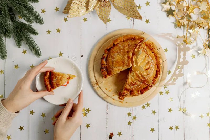 woman's hands take a piece of royal galette from a saucer on the table