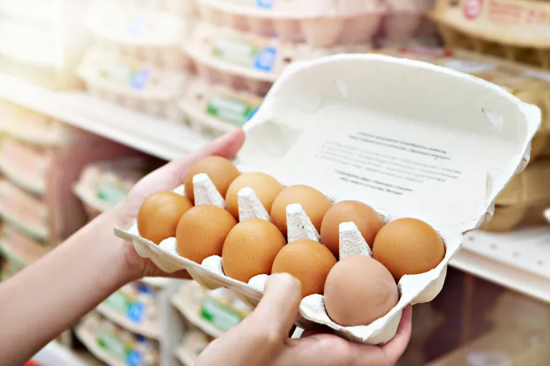 hands woman with packages of brown eggs in store