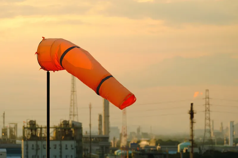 orange windsock on sunset sky and industrial estate background