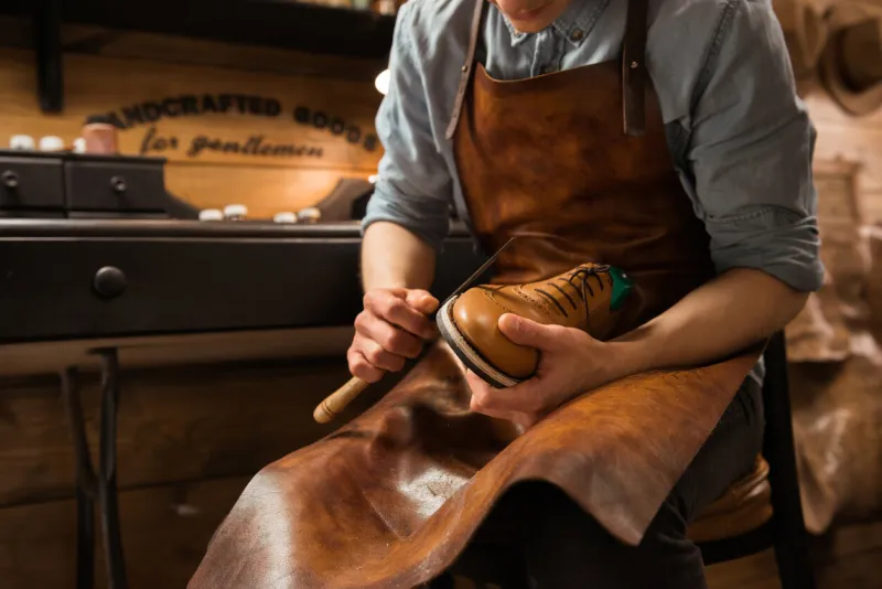 cropped picture of young shoemaker in workshop making shoes