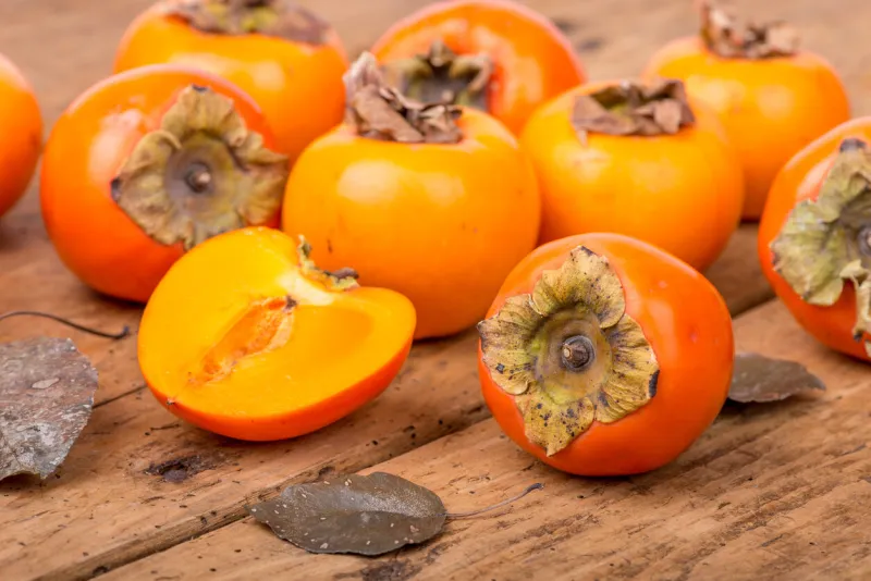 fresh ripe persimmon on a wooden table - selective focus