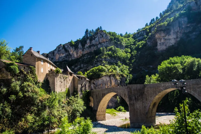 a beautiful shot of a stone arcade bridge near old stone houses in sainte-enimie, lozere, france