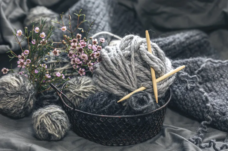 composition with gray threads for knitting, close-up of yarn with flowers