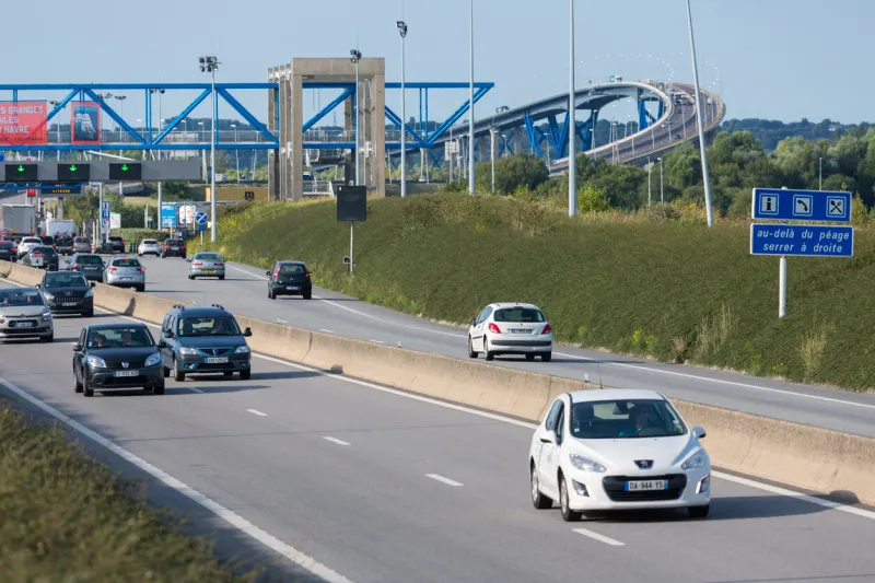 le havre, france - august 24, 2017  toll station with passing cars at bridge pont de normandie over river seine