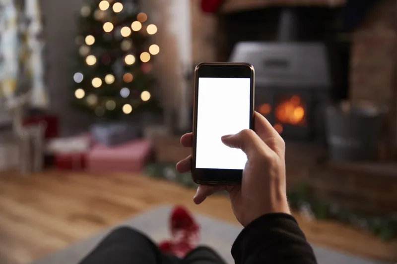 man using mobile phone in room decorated for christmas