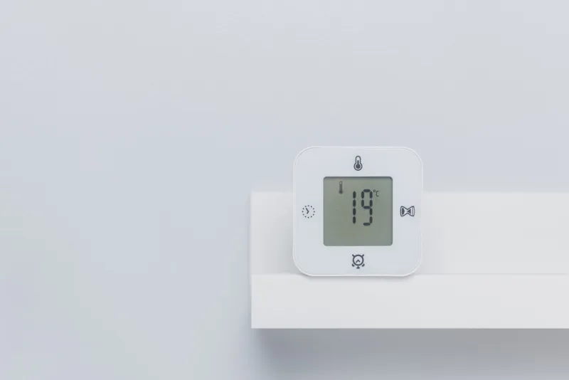 a white digital thermometer on the shelf with negative space room temperature concept