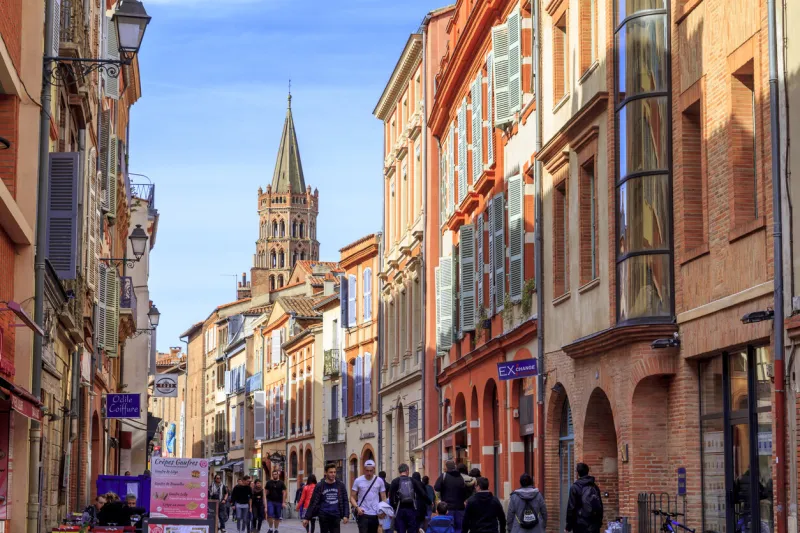 toulouse, france  april 01, 2018  people walking in the street in te city of toulouse, with san sernin basilica in the background