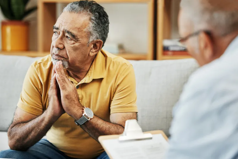 elderly man talking to a psychologist at a mental health, psychology and therapy clinic for session psychological therapist with clipboard for counseling checklist with senior male patient in office