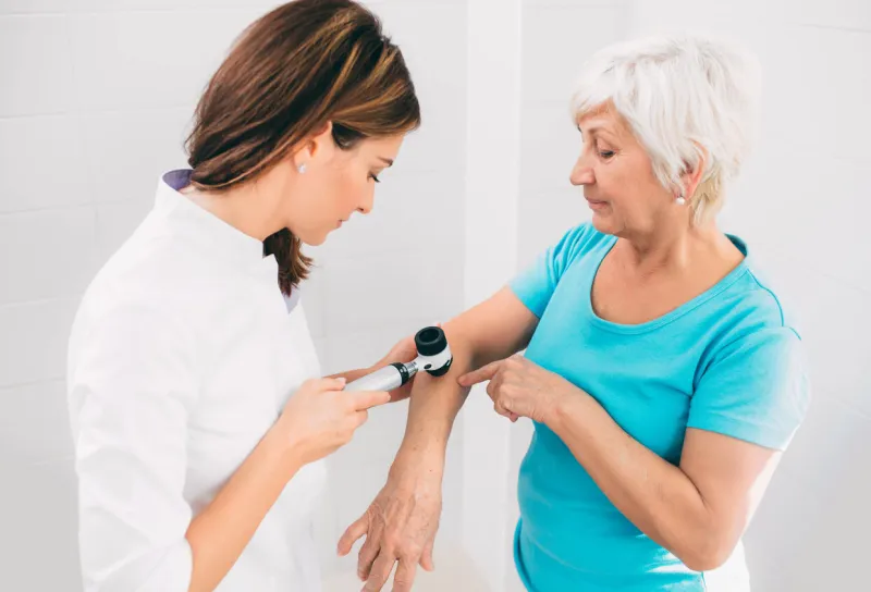 female dermatologist inspecting patient skin moles at clinic