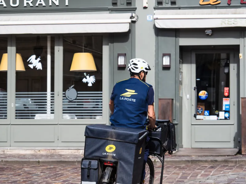 bayeux, france, august 21st 2024  a worker from the french postal company la poste on bike in the city of bayeux, france