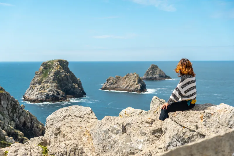 a young female tourist posing on the pen hir point on the crozon peninsula in french brittany