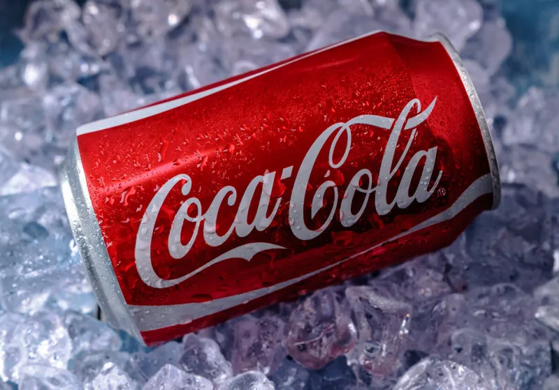 minsk, belarus - august 16, 2015  minsk, belarus - august 16, 2015  can of coca-cola on a bed of ice over a blue background