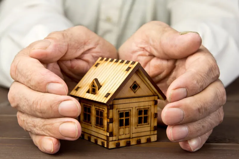 old man protecting house model with hands risk insurance the concept of mortgages and bank loans poverty rental property