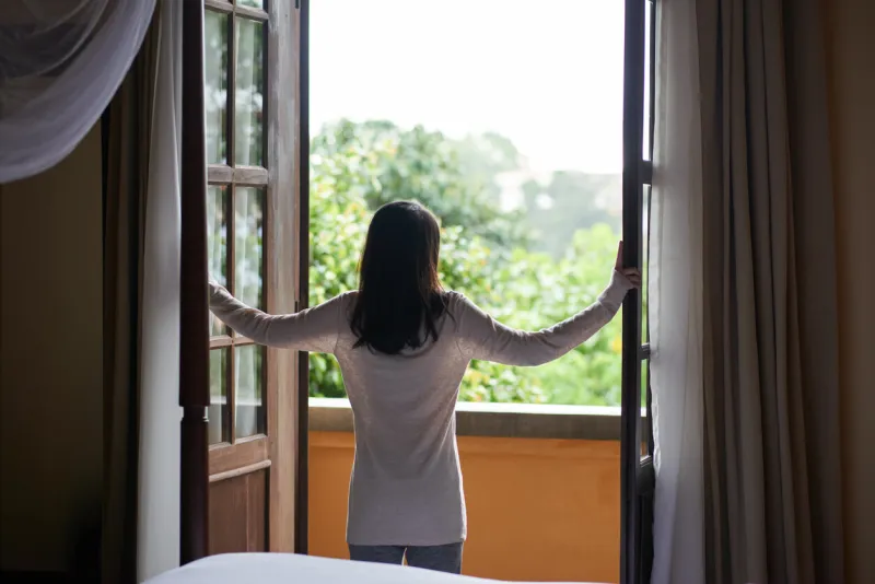 rear view of young woman enjoying view from balcony of her room