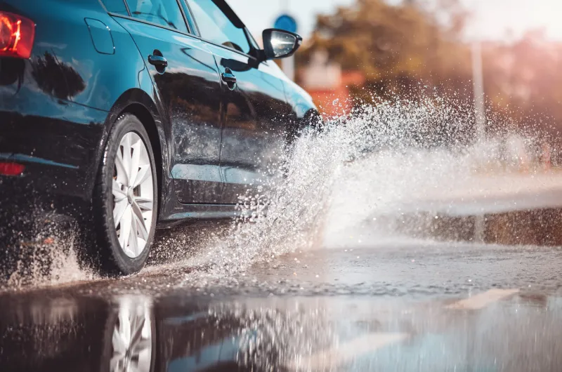 car driving through the puddle and splashing by water dangerous situation concept of road safety