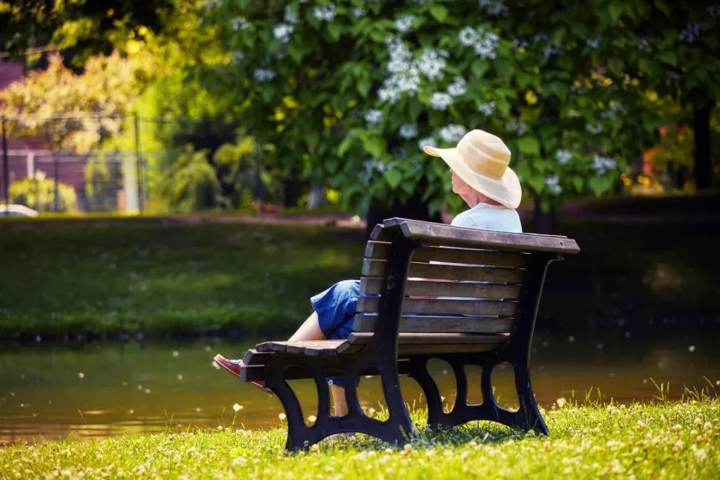 montreal, canada-june, 2018  elderly canadian woman wearing a hat sitting on a wooden bench and relaxing at the park on a sunny day editorial