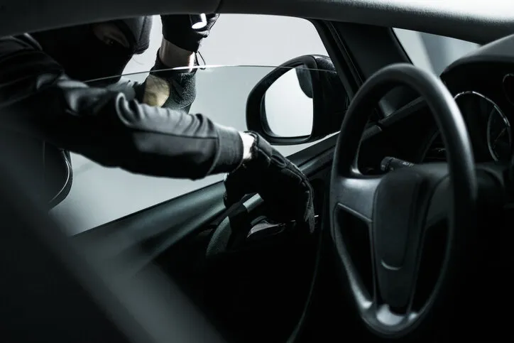 car thief trying to open car from the inside car insurance concept