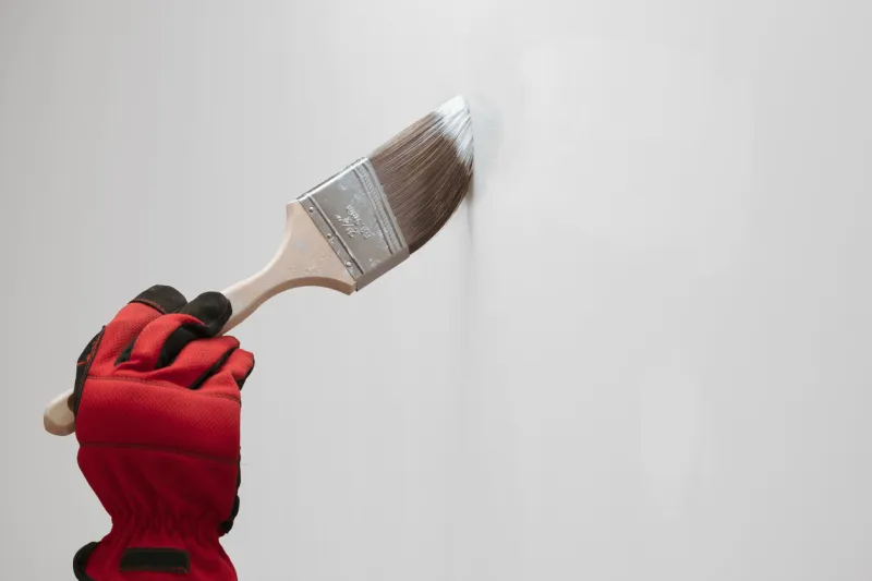 hand of unrecognizable person holding a paintbrush and painting a wall