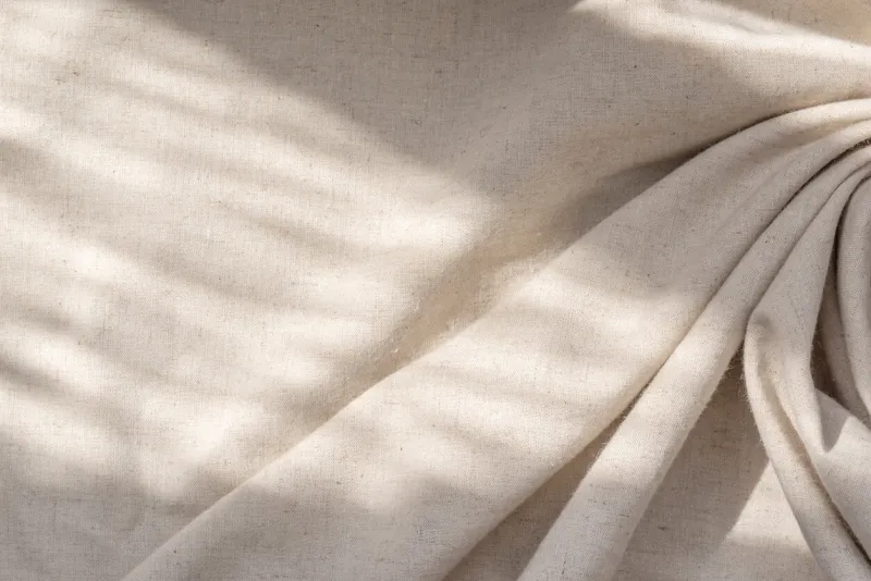 aesthetic natural textile background with an abstract sunlight shadow, neutral beige linen draped fabric, copy space