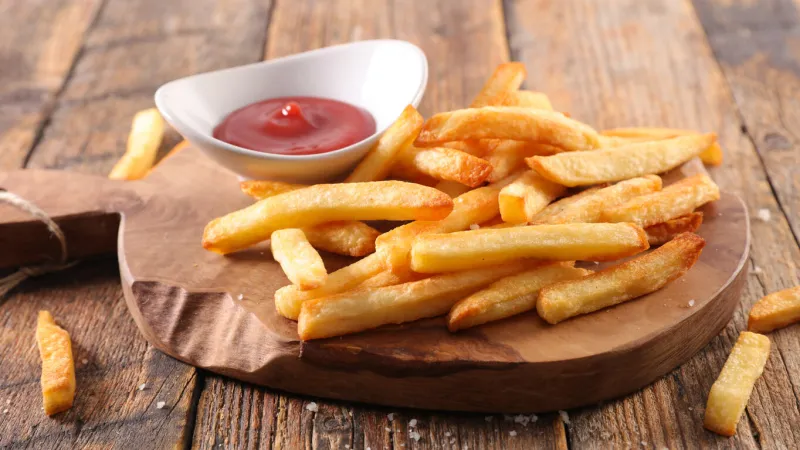 french fries and ketchup on wooden board