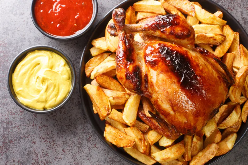 peruvian grilled chicken pollo a la brasa with fried potato and sauces closeup in the plate on the table horizontal top view from above