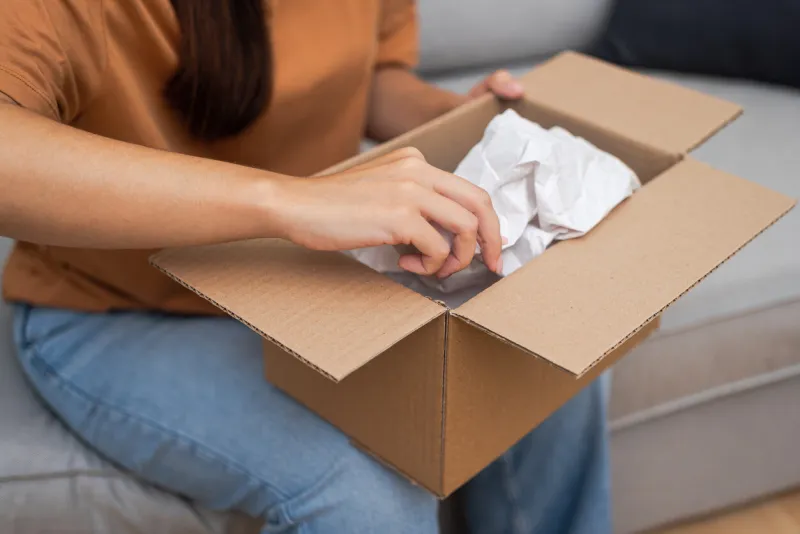 delivery happiness  seated on a sofa, a satisfied woman unwraps her online shop purchase, celebrating the convenience of shipping and delivery