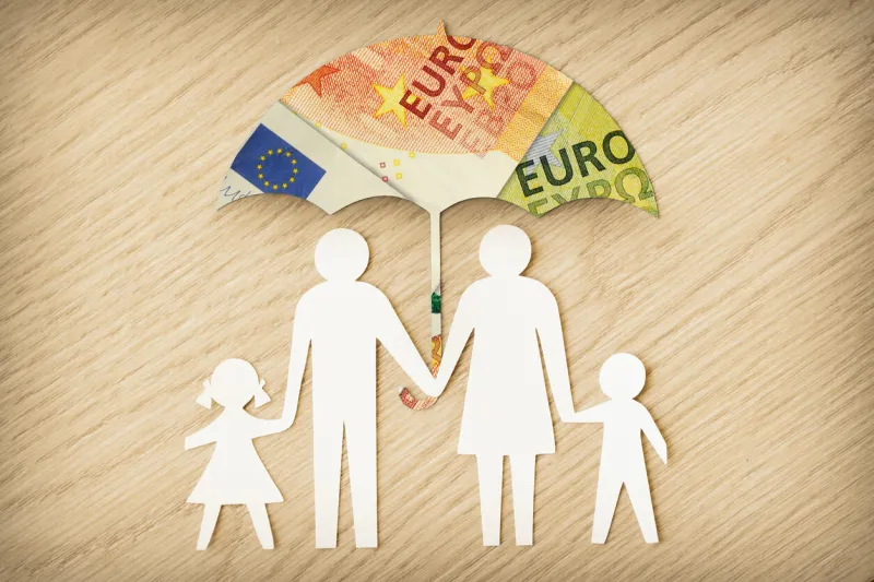paper family silhouette with umbrella made of euro banknotes on wooden background - concept of family financial protection