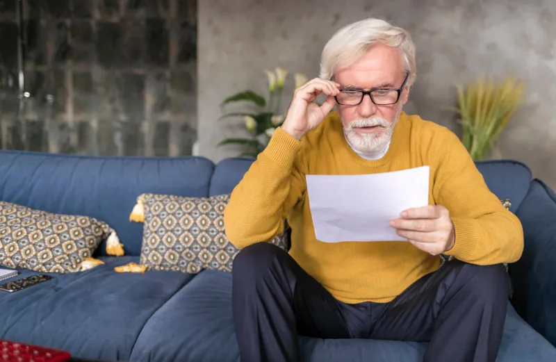 adult man reading letter with confused face from social service